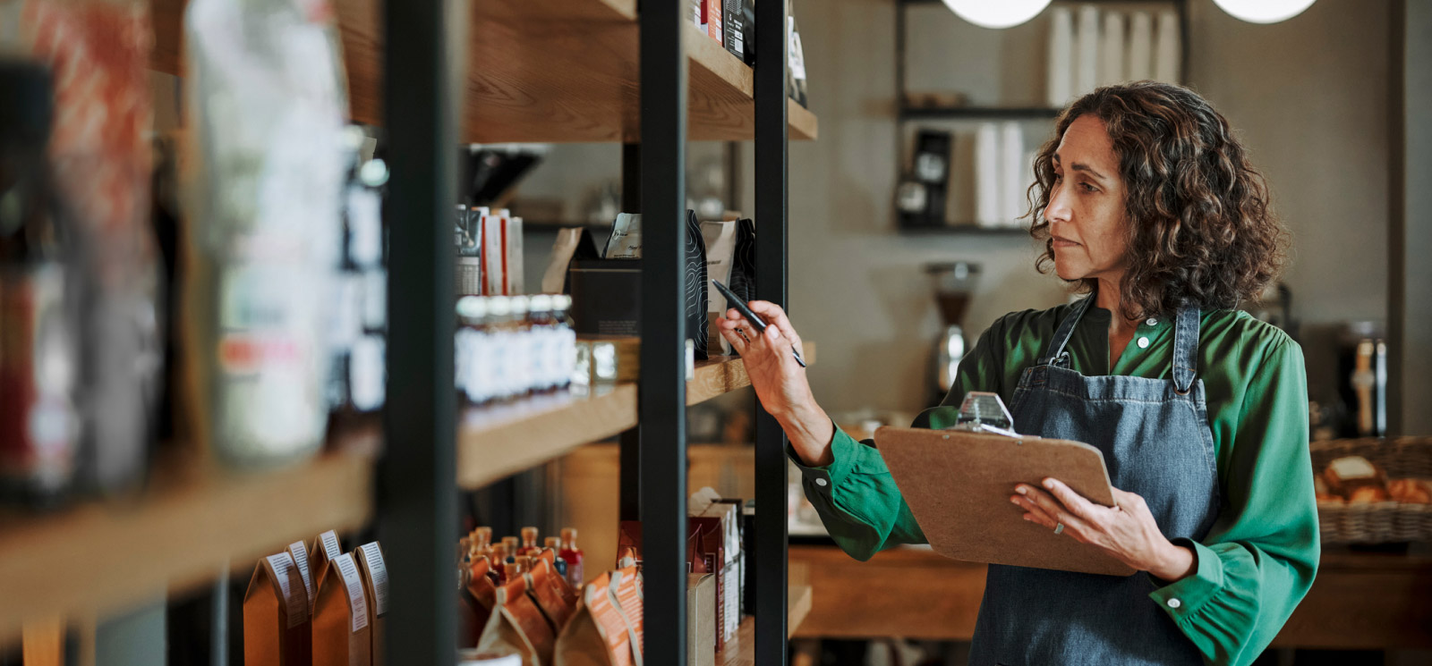 small business owner tracking inventory on her shelf with a pen and clipboard