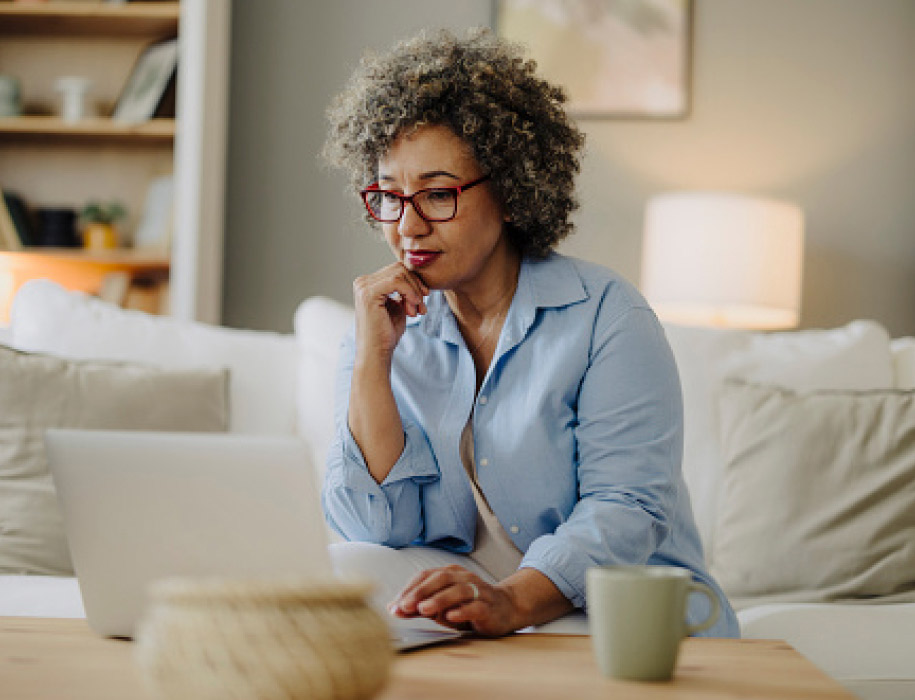 woman using computer, sitting in her living room with a cup of coffee