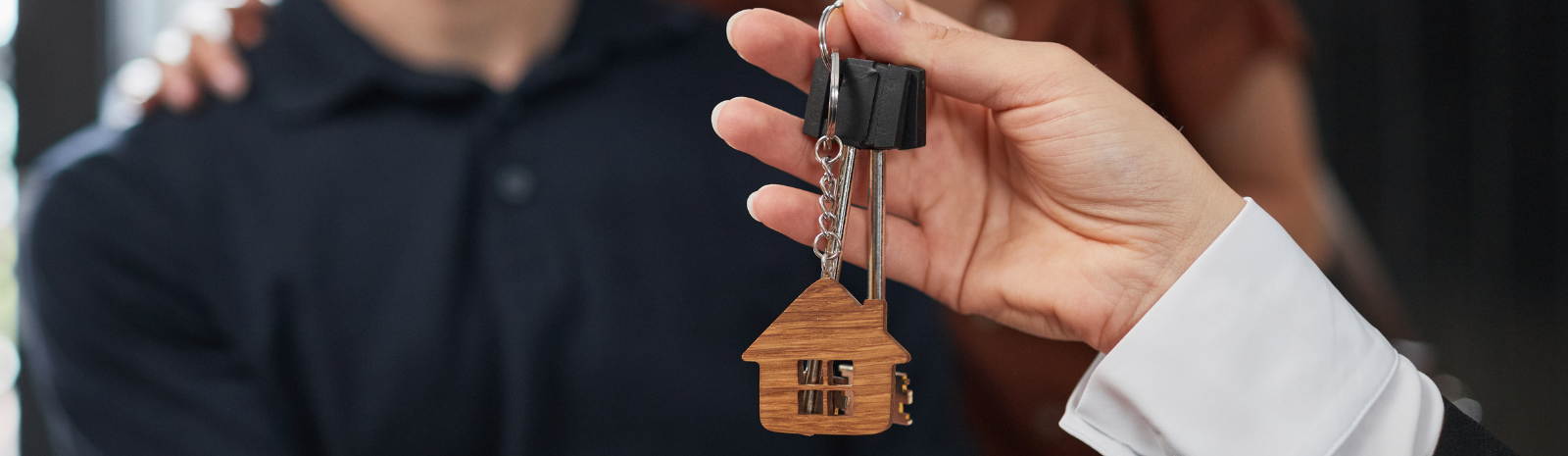 Closeup of keys to a new home being given to man and woman.